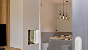 Uma sala de estar moderna com televisão, móveis de madeira, um sofá cinza e um espaço de jantar com mesa e cadeiras de madeira.