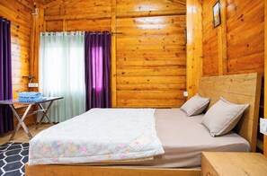 A wooden cabin bedroom with a bed, pillows, a table, and a chair. - Hotel Seven Lake Stays Uttarkhand (Nainital)