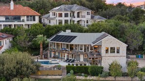 Een tweelaags huis met een zwembad, zonnepanelen en een gevel van natuursteen.
