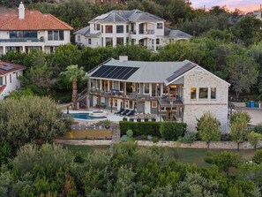Ein zweigeschossiges Haus mit Swimmingpool, Solaranlage und Natursteinfassade.