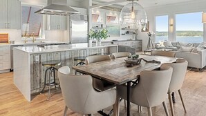 Een moderne keuken met een centraal eiland, roestvrijstalen apparatuur en een groot raam met uitzicht op een prachtig landschap.