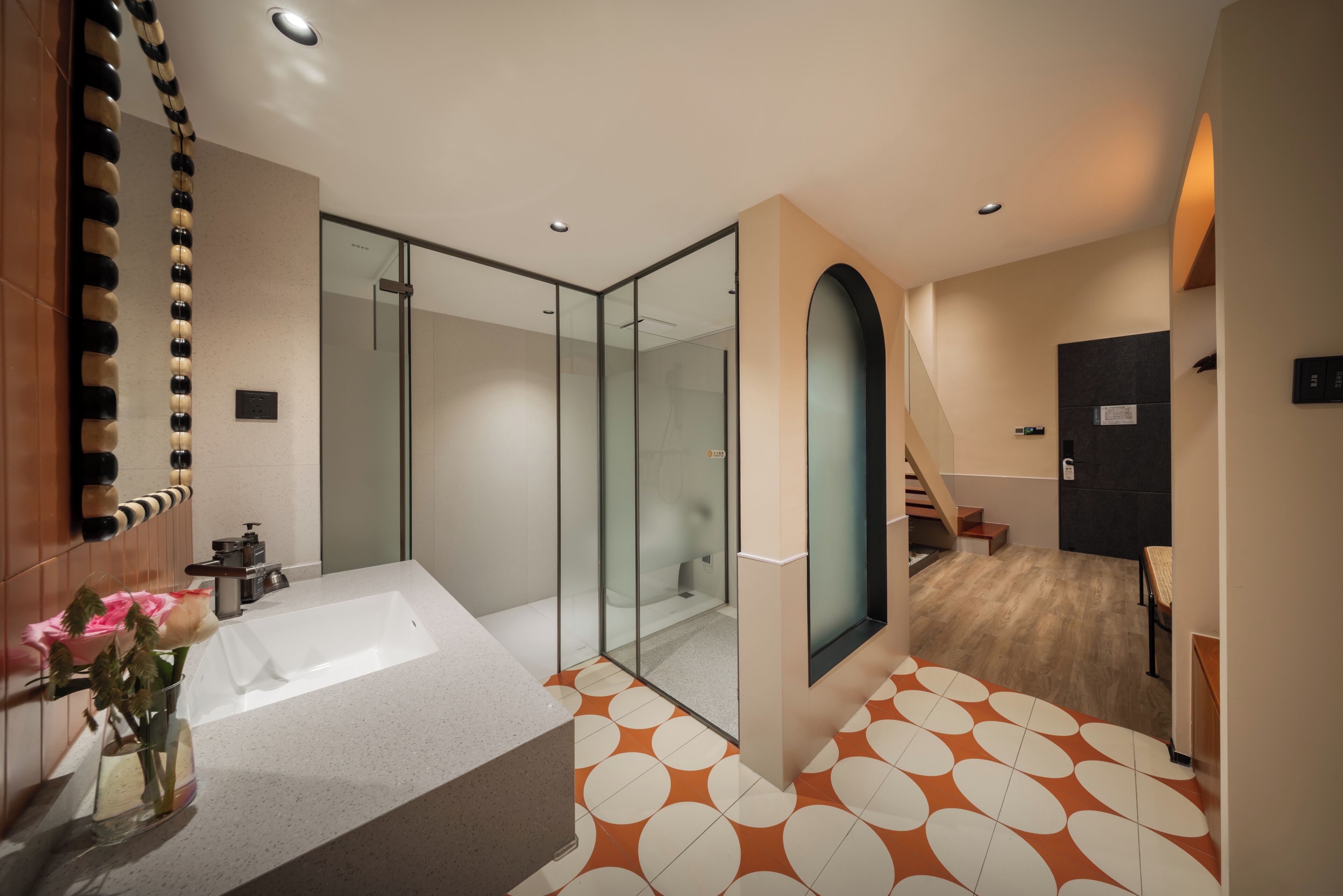 A modern bathroom with a large bathtub, a glass shower enclosure, and a patterned floor.