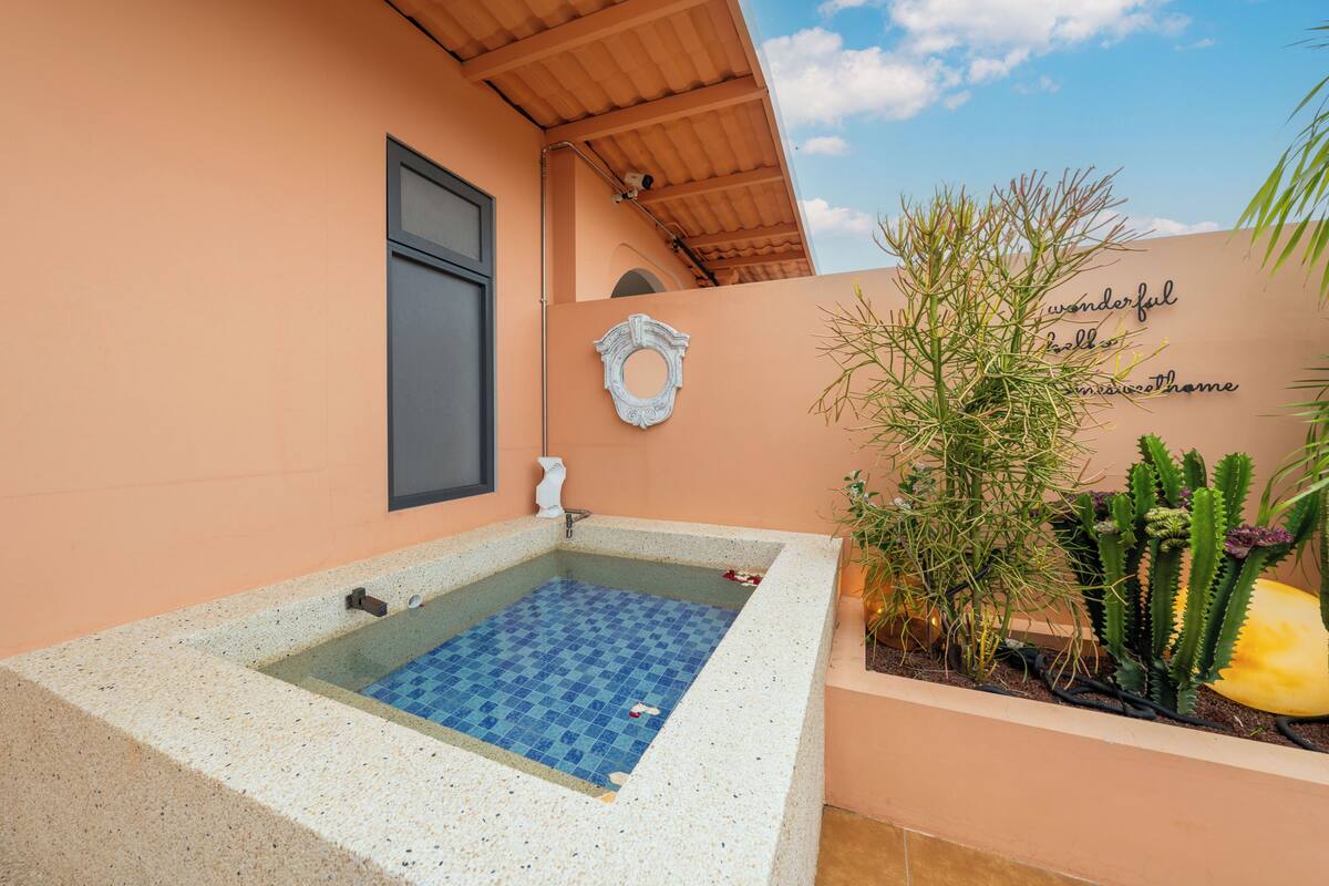 Un área de spa con un jacuzzi con azulejos, un adorno de pared y un jardín de cactus.