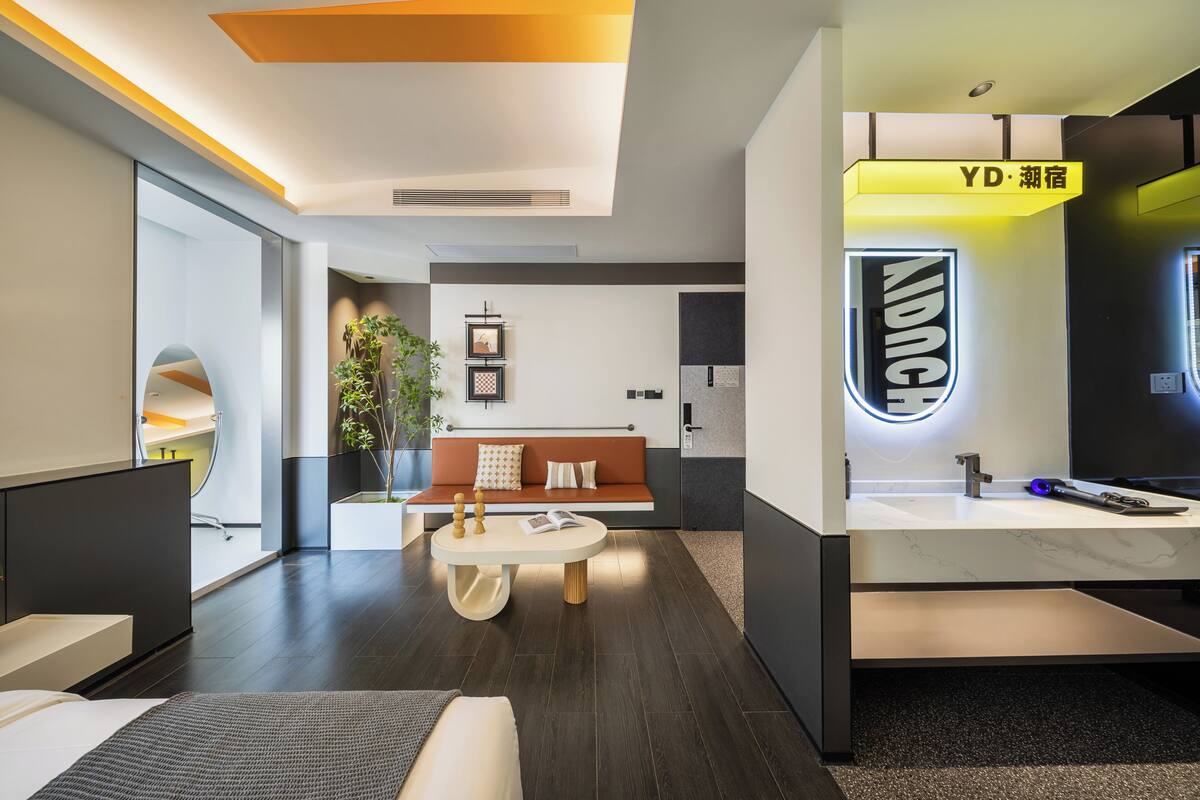 Un moderno vestíbulo de hotel con un sofá, una mesa redonda, un mostrador de recepción y un letrero con el nombre del hotel.