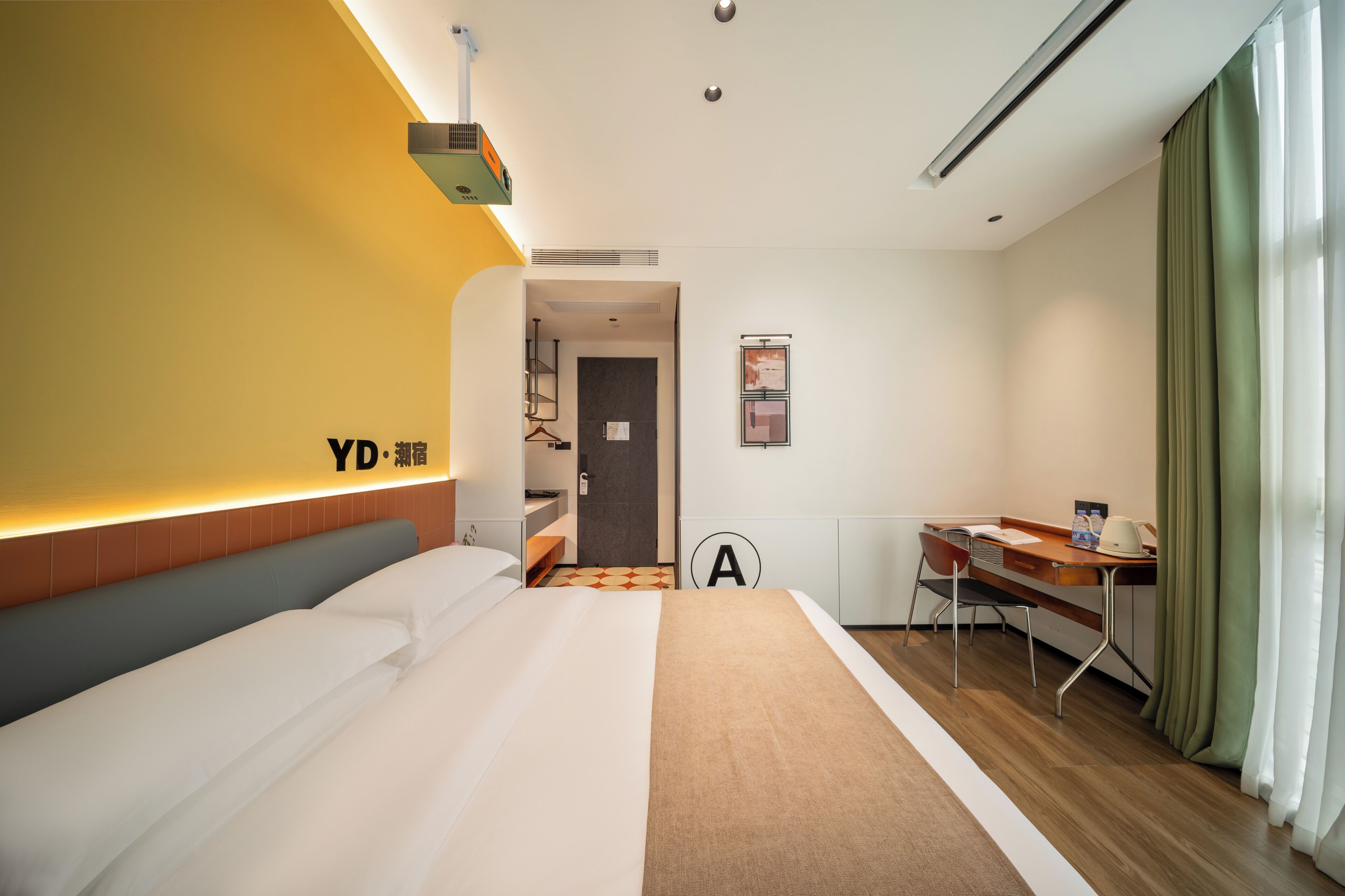 Une chambre d’hôtel comprenant un lit, un bureau, une chaise, une armoire et une salle de bain visible à travers une porte ouverte.