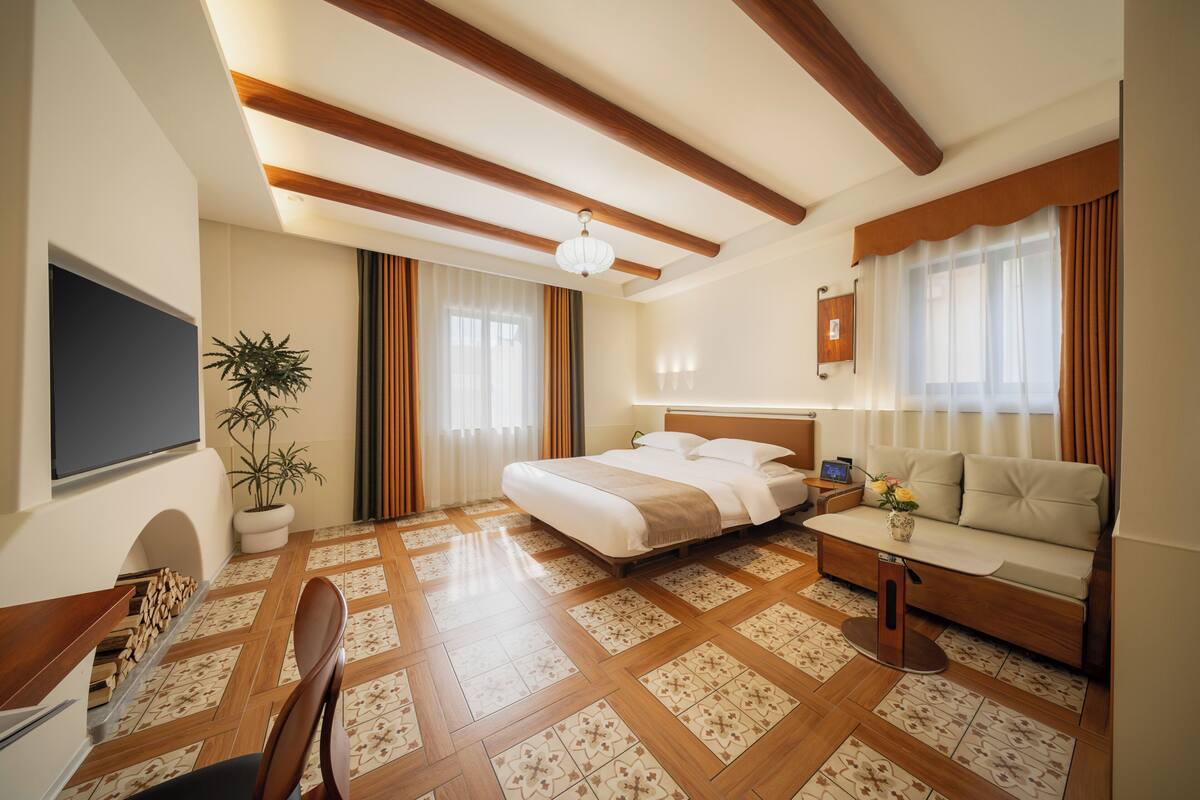 Una habitación de hotel con cama, sofá, televisor y una planta en maceta.