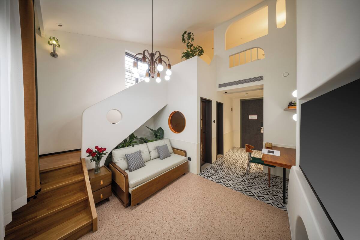 Un interior moderno con una escalera, un sofá, una mesa de comedor y un televisor.