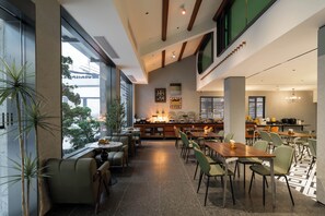 Un espace de restauration moderne, doté de hauts plafonds, de grandes fenêtres et d’une variété d’agencements de sièges.