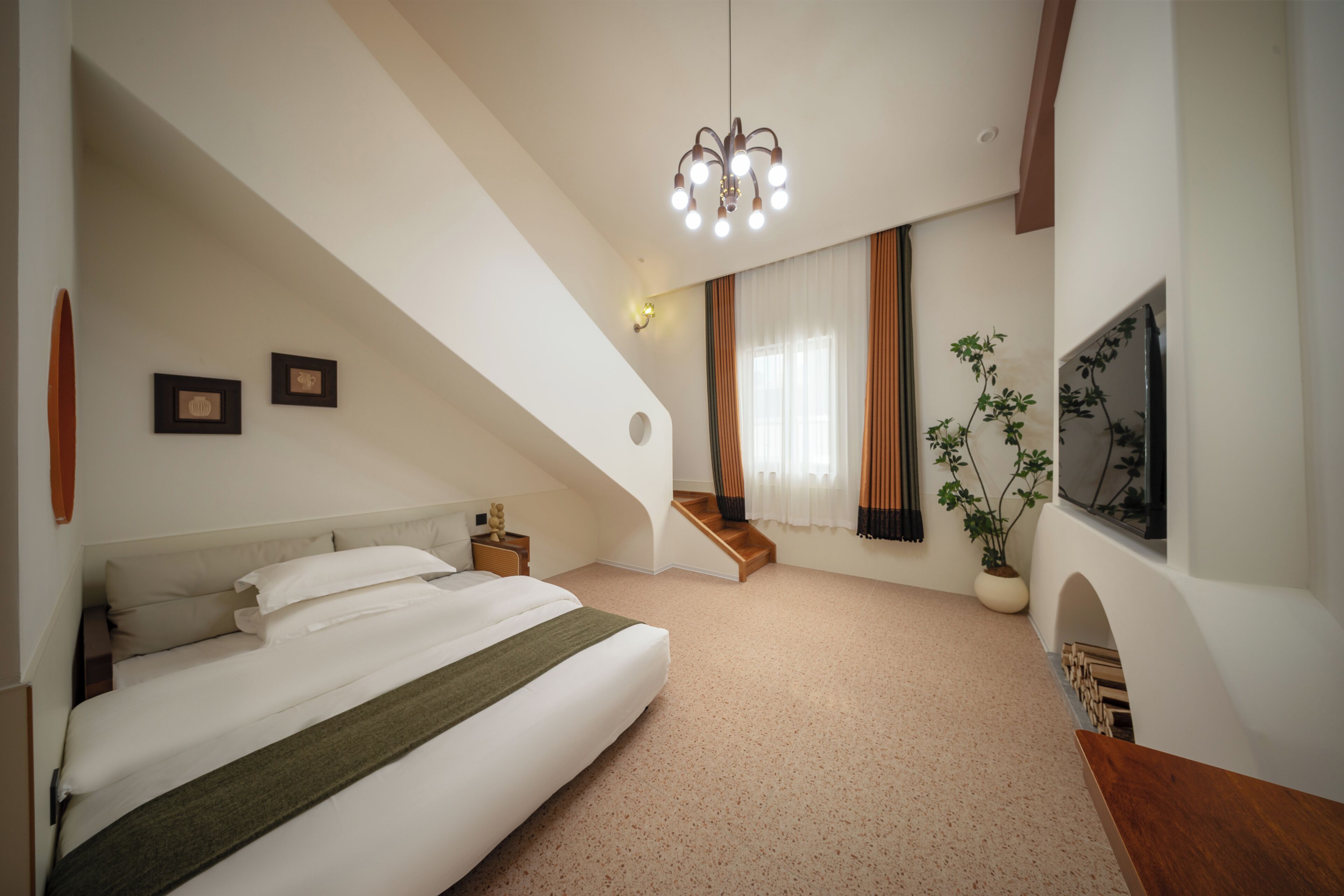 A bedroom with a bed, a staircase, a potted plant, and a wall-mounted TV.