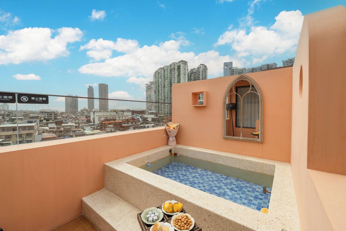 Una terraza en la azotea con una pequeña piscina, un ventanal con vistas a la ciudad y un letrero con información de orientación.