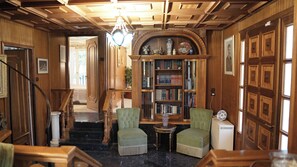 A room with a wooden staircase, two green armchairs, a small table, a bookshelf, and a white radiator. - Wonderful Villa in Lagonisi on the Athenian Riviera (Kalivia Thorikou)