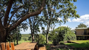 A wooden picnic table in a garden with trees and a house in the background. - Large family home in a quiet rural location. (Isis Central)