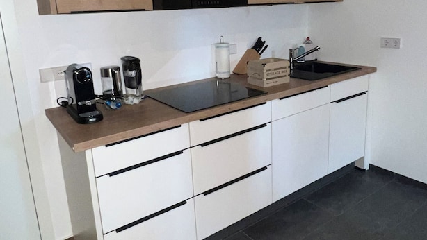 A modern kitchen with white cabinets, a black countertop, and a built-in stove. - PAULINEN Residence - Live comfortably - Arrive flexibly (Detmold)