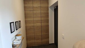 A narrow hallway with a wooden panel wall, a shoe rack, and a door leading to another room. - PAULINEN Residence - Live comfortably - Arrive flexibly (Detmold)