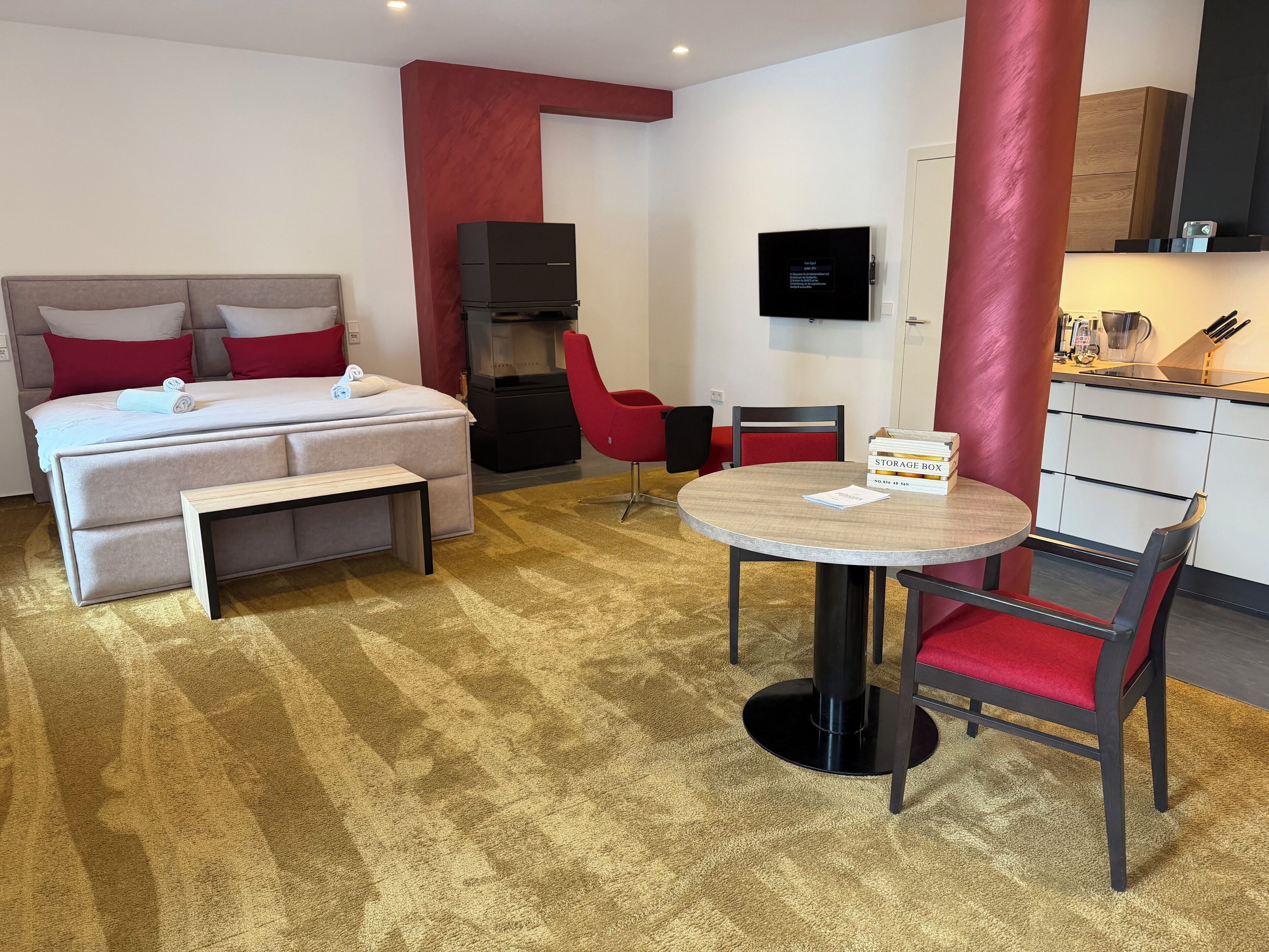 Ein Hotelzimmer mit einem Bett, einem Schreibtisch, einem Sessel, einem Fernseher und einer Küchenzeile.