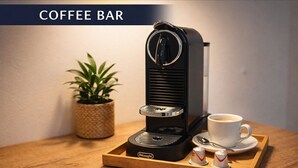 A coffee bar with a Delonghi espresso machine, a cup of coffee, a tray, and a small potted plant. - PAULINEN Residence - Live comfortably - Arrive flexibly (Detmold)