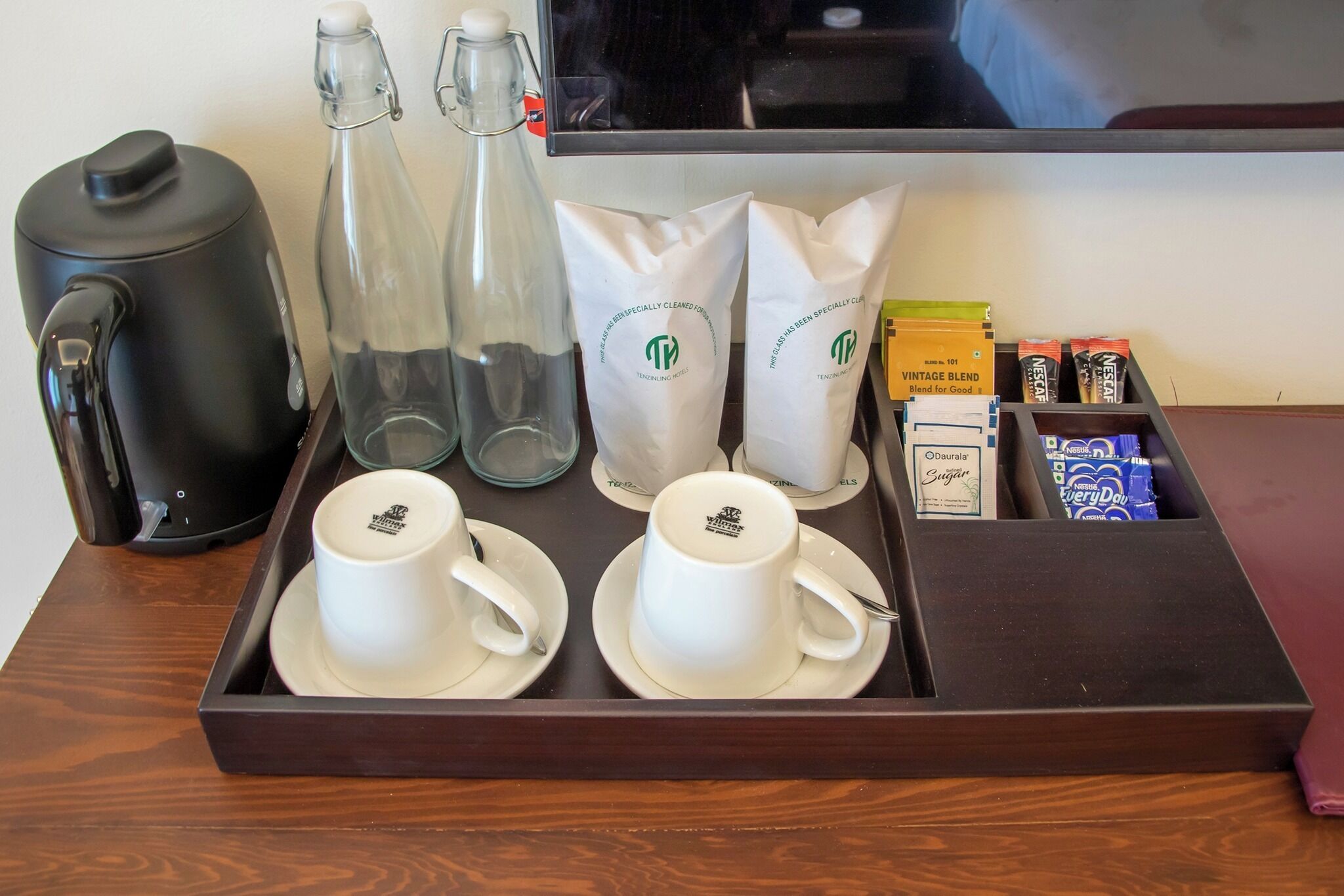 Un plateau avec des tasses à café, une machine à café, des bouteilles et des paquets de café.