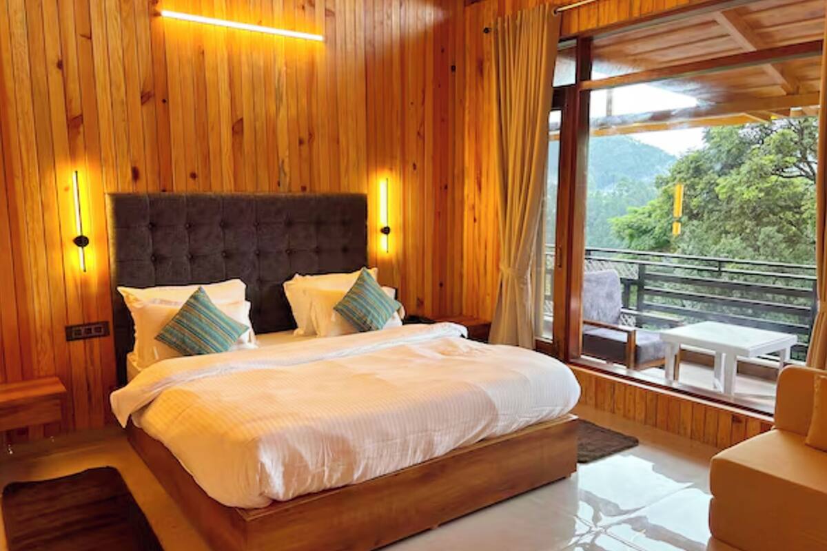 A wooden-paneled room with a large bed, two bedside lamps, and a view of the outdoors.
