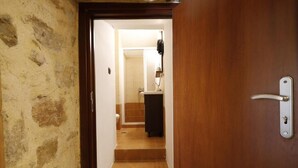 A hallway leading to a bathroom with a sink and toilet. - Tholos by Praxithea Stone House & Pool (Chania)