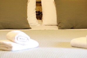 Cama com almofadas e toalhas dobradas.