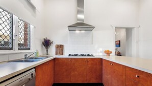 A modern kitchen with wooden cabinets, a stainless steel range hood, and a Bosch dishwasher. - Heritage Hideaway - North Perth (North Perth)