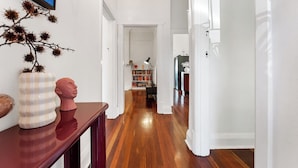 A hallway with wooden flooring, white walls, and a bookshelf in the distance. - Heritage Hideaway - North Perth (North Perth)