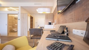A modern hotel room with a wooden desk, a laptop, a notebook, and a yellow chair. - Family apartment for 2 adults and 2 children in the south of Graz 24-7 check-in (Graz)