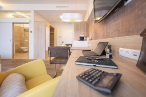A modern hotel room with a wooden desk, a laptop, a notebook, and a yellow chair. - Family apartment for 2 adults and 2 children in the south of Graz 24-7 check-in (Graz)