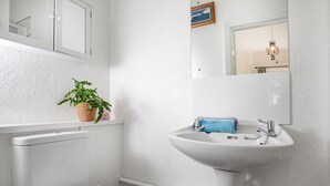Ein Badezimmer mit Toilette, Waschbecken, einem Spiegel und einer Topfpflanze.