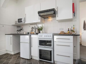 Une cuisine de taille réduite, dotée d’appareils électroménagers blancs, d’un four à micro-ondes, d’une cuisinière et d’un petit réfrigérateur.