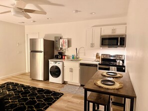 A compact kitchen with a refrigerator, microwave, stove, and washing machine.