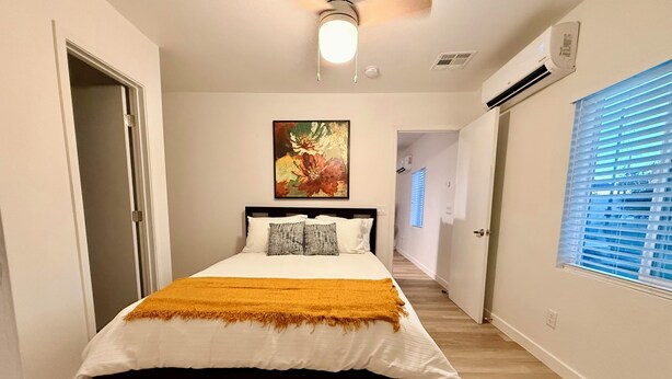 Ein Schlafzimmer mit Bett, einem Gemälde und einem Flur, der in einen anderen Raum führt.