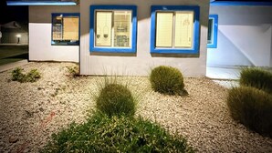 Ein modernes Haus mit zwei Fenstern, einer Schotterauffahrt und kleinen Büschen.