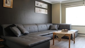 Een moderne woonkamer met een hoekbank, een houten salontafel en kunst aan de muur.