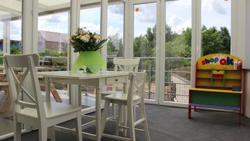 A room with a table and chairs, a vase with flowers, and a colorful bookshelf.