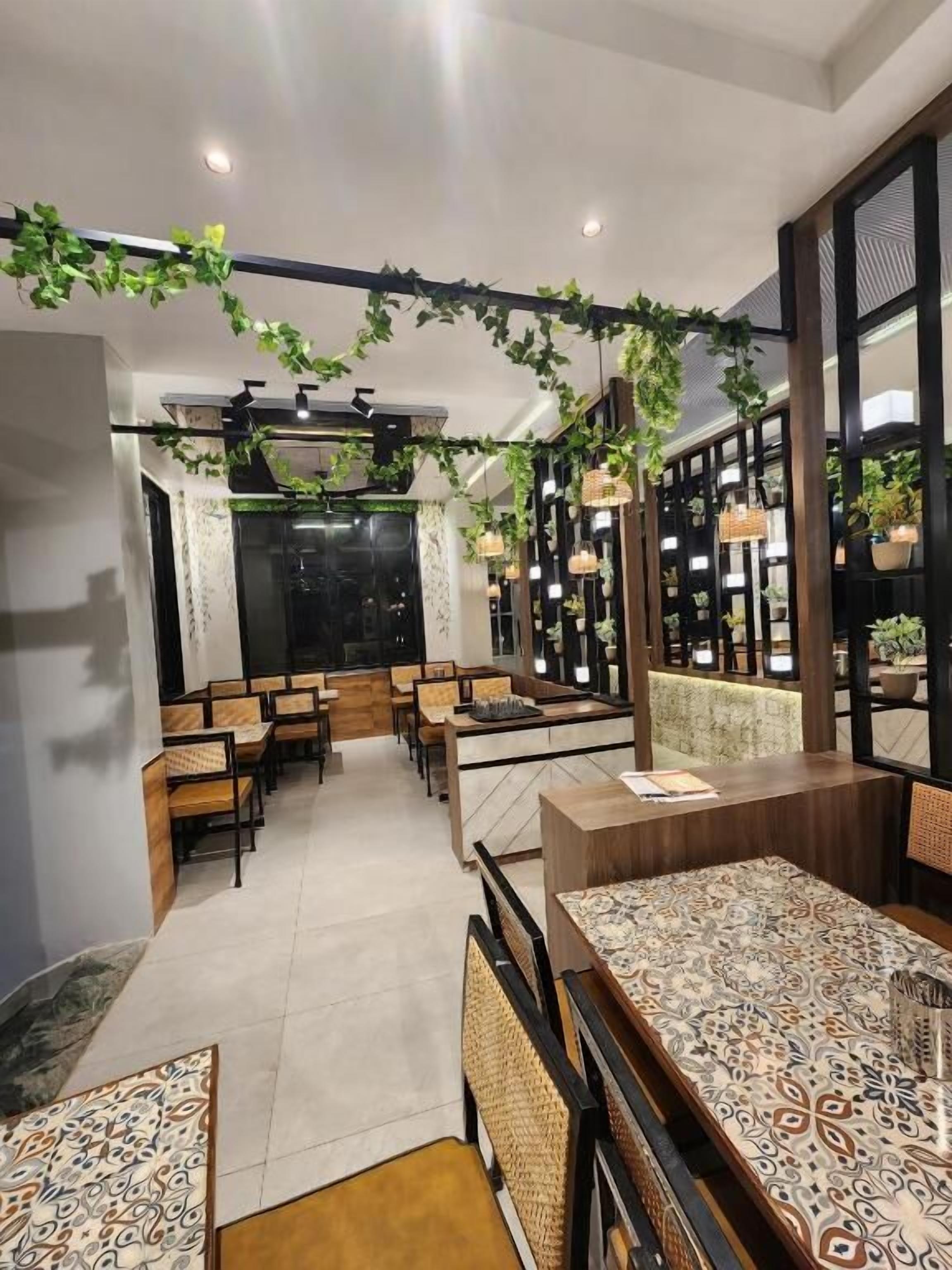A restaurant with a central island, wooden furniture, hanging plants, and a modern interior design.