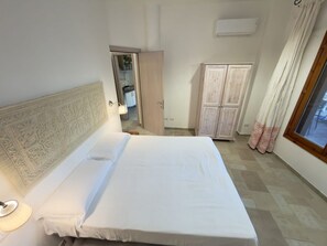 Ein Schlafzimmer mit Bett, Kleiderschrank, Spiegel und Klimaanlage.