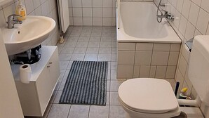 A bathroom with a toilet, bidet, sink, and a window.