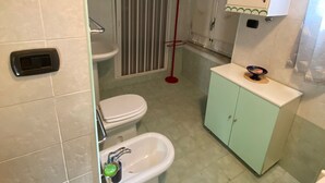 Ein Badezimmer mit Toilette, Bidet, Waschbecken und Duschbereich.