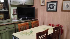 Ein Essbereich mit Tisch, Stühlen, einem Fernseher und Bildern an der Wand.