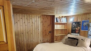 Ein Zimmer mit Holzvertäfelung, einem Bett, einem Bücherregal und einem Poster an der Wand.