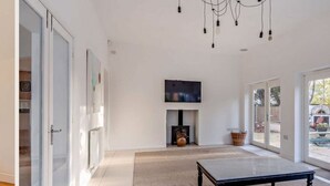 Un interior moderno con chimenea, televisor y un gran ventanal corredera que da a un espacio exterior.