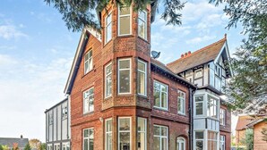 Una casa en esquina con una imponente torre de ladrillo, grandes ventanales y una combinación de estilos arquitectónicos tradicionales y modernos.