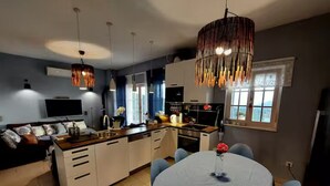 A modern kitchen with a central island, pendant lighting, and a dining area with a round table. - Villa Mediterranea Seaview Primošten (Primosten)