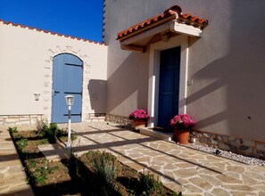 A building with a blue door and a white wall, a stone pathway, and potted plants. - Villa Mediterranea Seaview Primošten (Primosten)