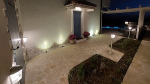 A building with a stone-paved entrance, a blue door, and potted plants. - Villa Mediterranea Seaview Primošten (Primosten)