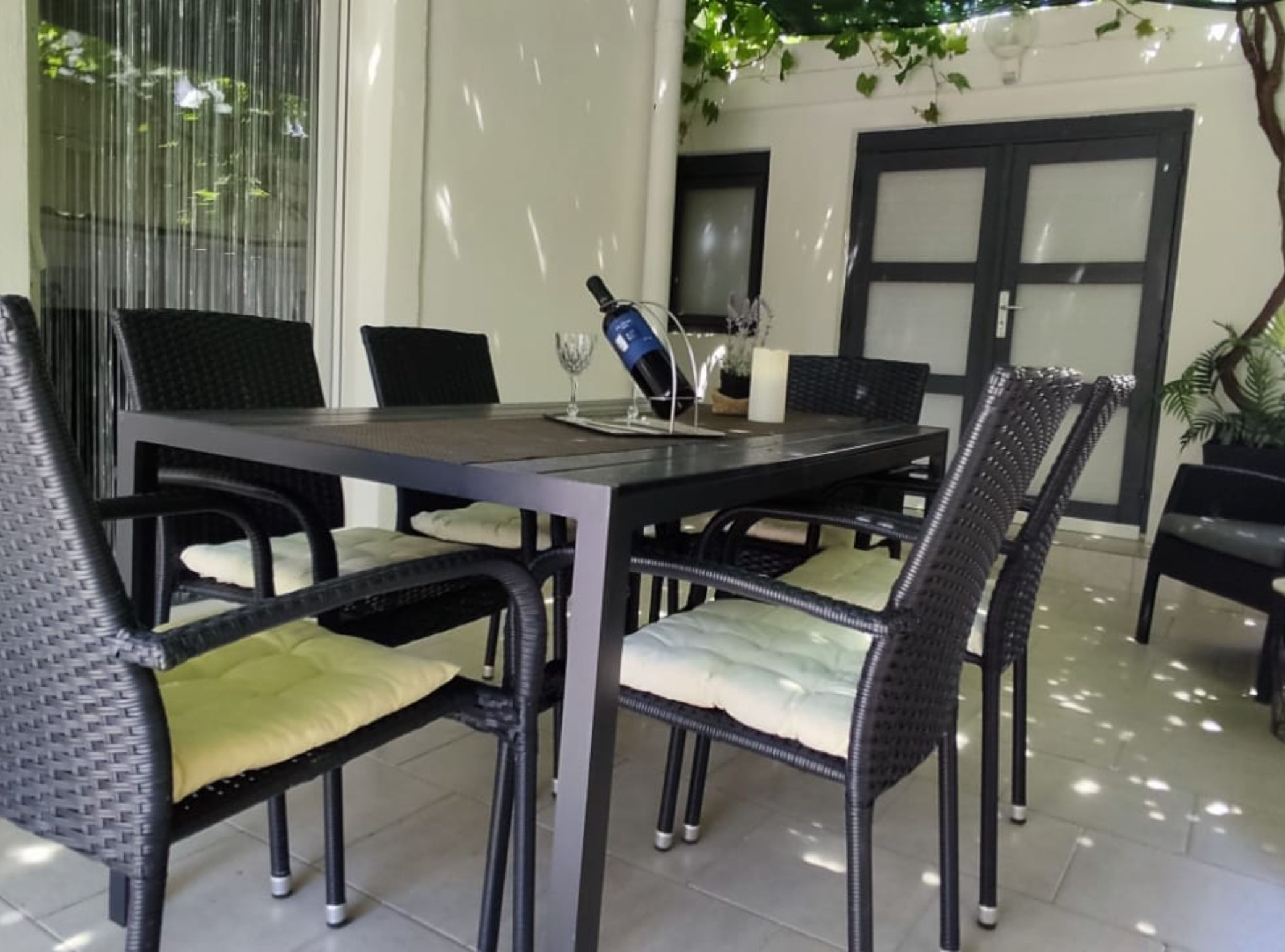 Un comedor con una mesa, sillas, un florero y una botella.