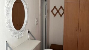 Un baño con tocador blanco, un espejo grande, un armario de madera y una puerta con decoración geométrica.