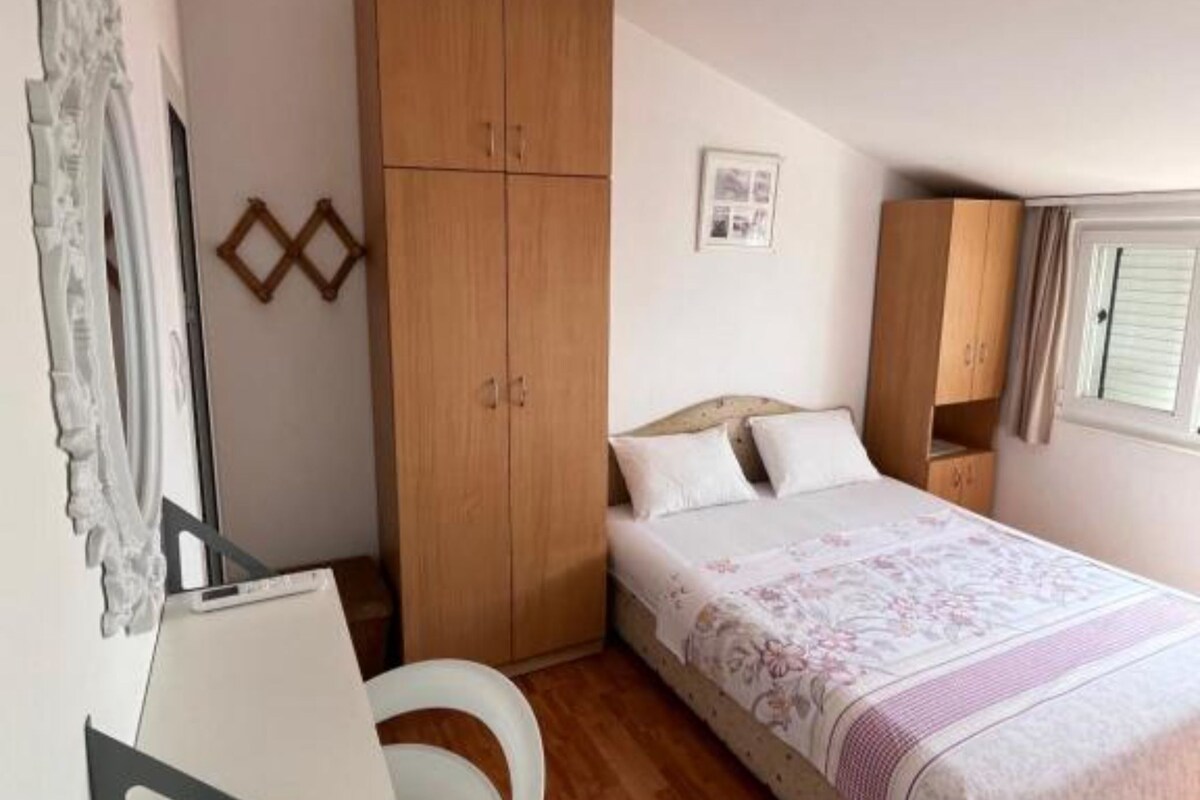 Ein Schlafzimmer mit einem Bett, einem Holzschrank, einem Schreibtisch und einem Fenster.
