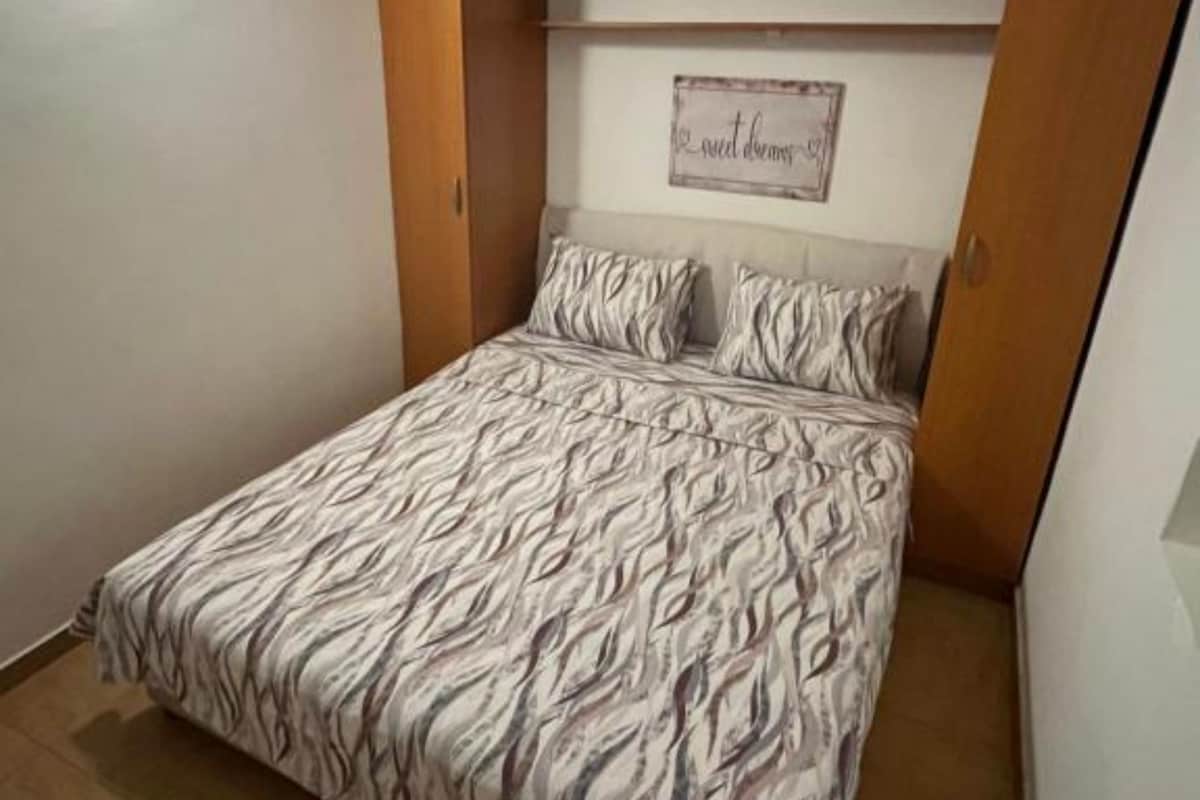 Ein Schlafzimmer mit Bett, Kissen, einem an der Wand befestigten Schild und einer Holztür.
